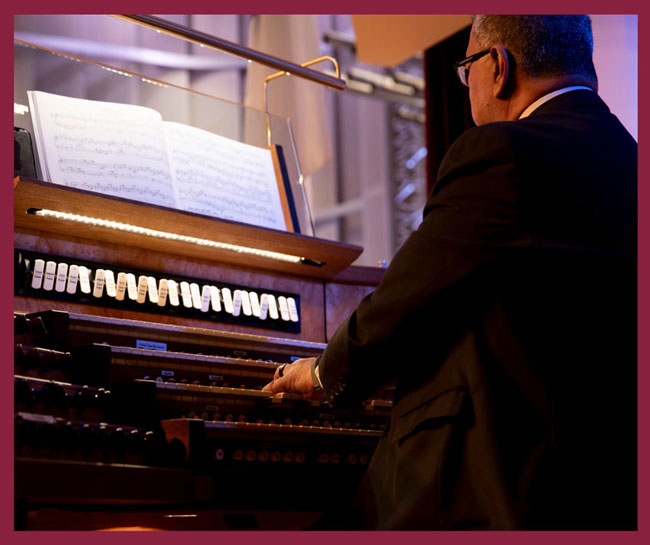 Musician playing an organ during a School of Dentistry dedication ceremony, with sheet music visible on the instrument