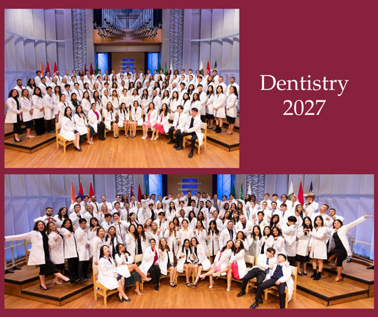 Students from the School of Dentistry Class of 2027 pose together on stage during a dedication ceremony, wearing white coats in a formal group setting