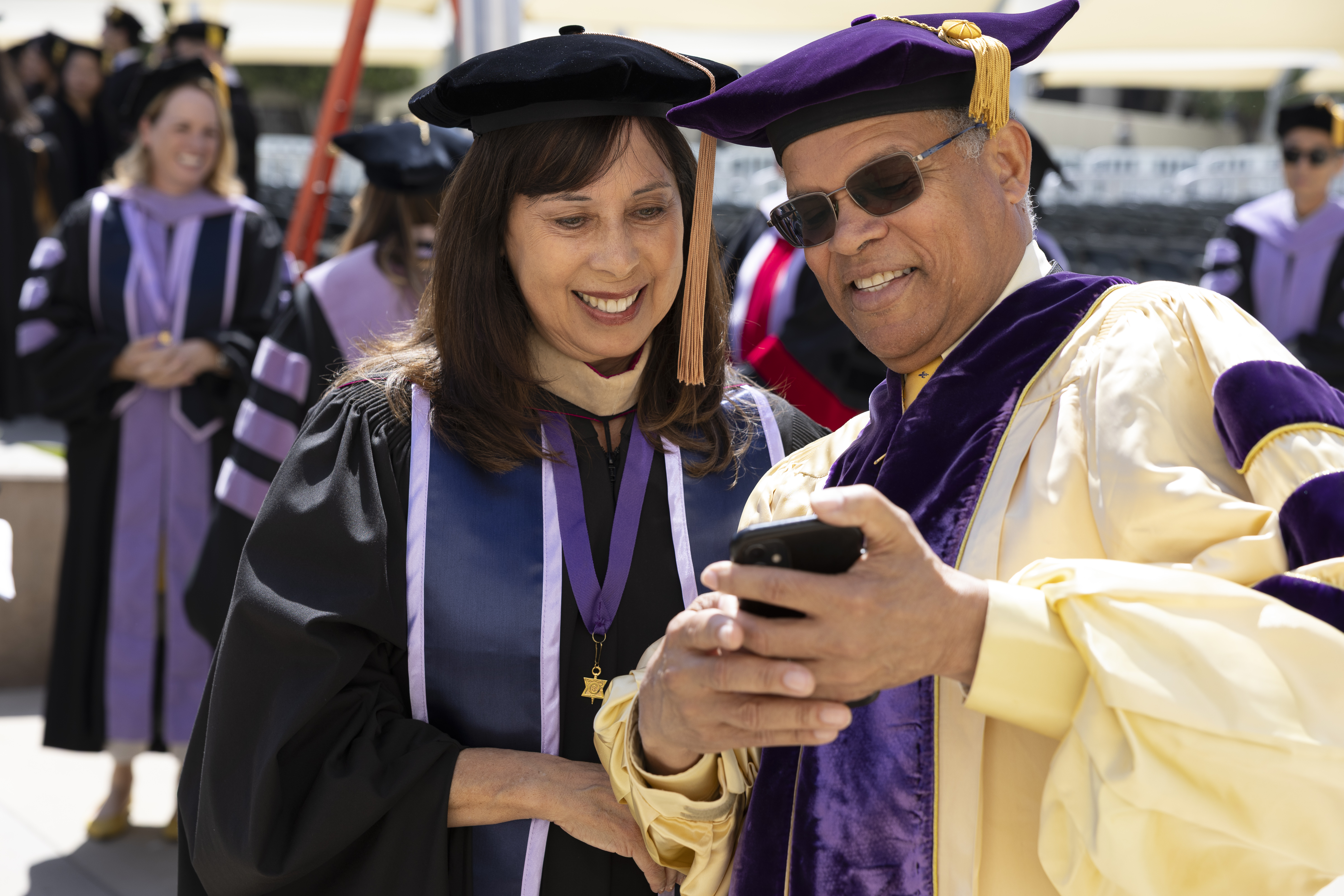 couple in regalia looking at phone