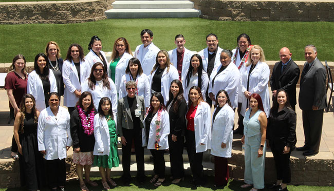Large group of people wearing white coats standing together outdoors on tiered steps