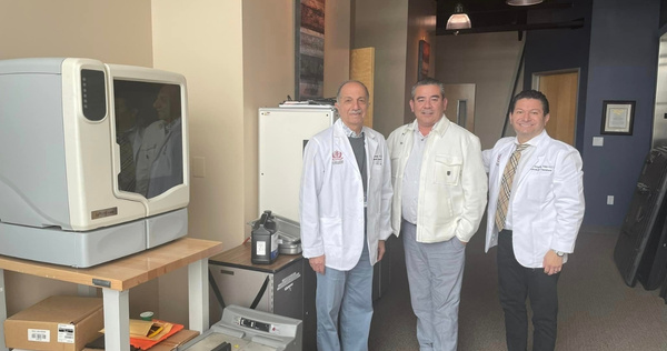 Dental faculty members standing with donated orthodontic equipment inside the School of Dentistry