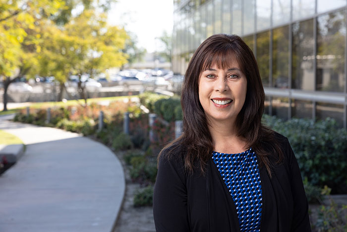 Professional portrait of Esther Forder standing on a walkway outside a modern office building