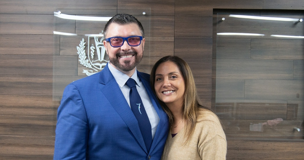 Dr. Vlad Loshkarev and Dr. Laura Mego standing together indoors in front of a School of Dentistry office wall with LLUSD logo in background..