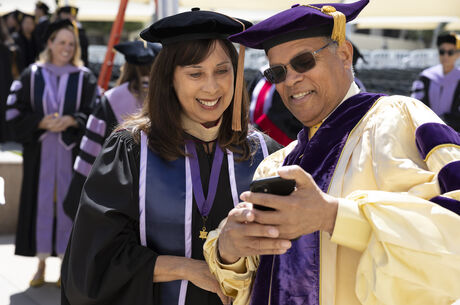 couple in regalia looking at phone