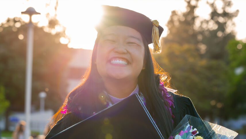 female graduate in regalia smiling joyfully