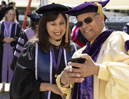 couple in regalia looking at phone