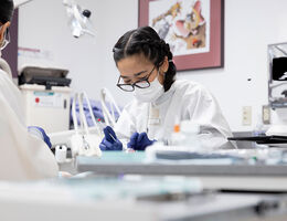 Dental Students wearing protective dental equipment working on a patient in a clinical treatment room