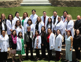 Large group of people wearing white coats standing together outdoors on tiered steps