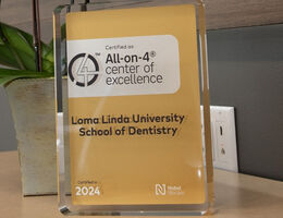 ll-on-4 Center of Excellence award displayed for Loma Linda University School of Dentistry, certified in 2024.