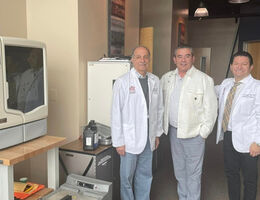 Dental faculty members standing with donated orthodontic equipment inside the School of Dentistry